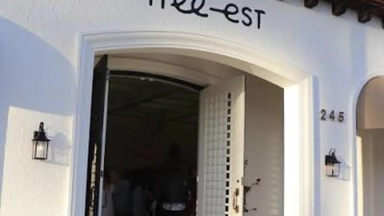White stucco storefront with red tile roof, open arched doorway, and free-est sign above entrance.