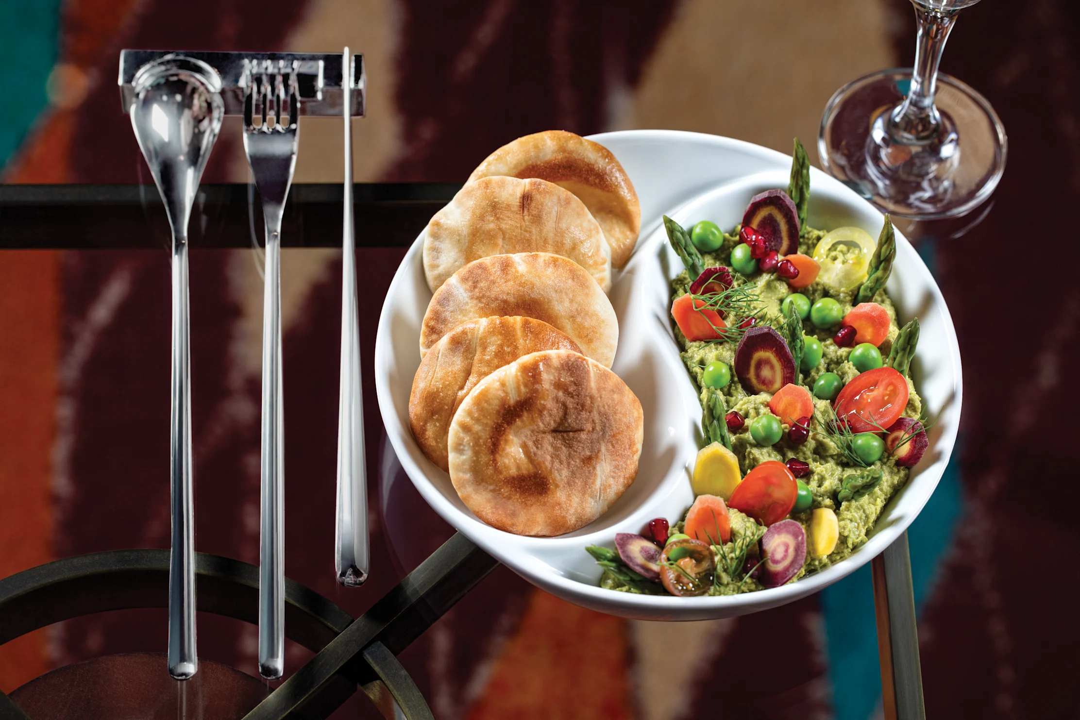 White plate with pita bread and colorful vegetable salad with asparagus, tomatoes, and beets.
