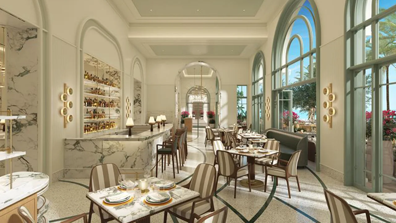 Elegant restaurant interior with arched windows, marble bar, set dining tables, and natural light.