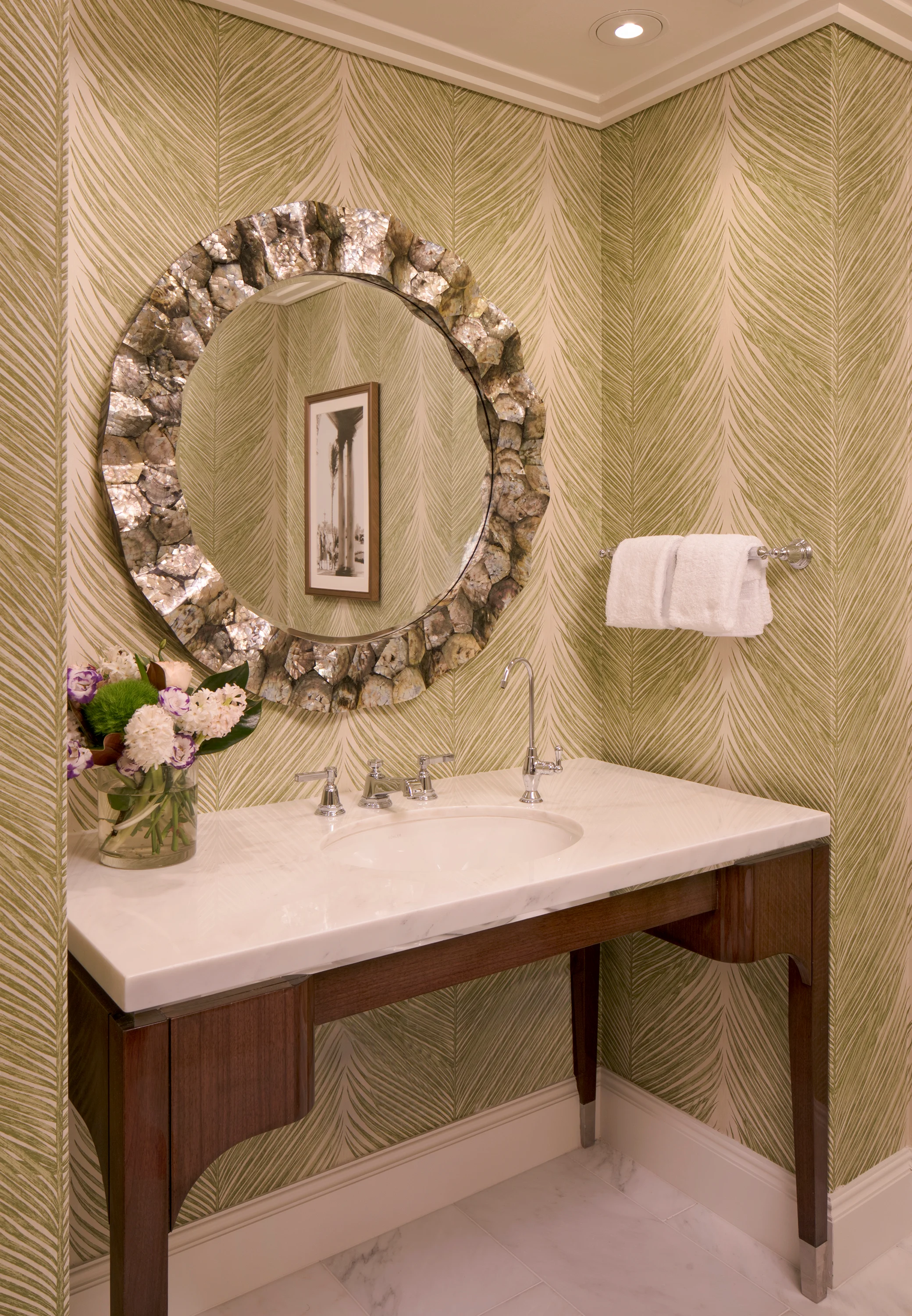 Elegant powder room with gold chevron wallpaper, ornate circular mirror, and white vanity.
