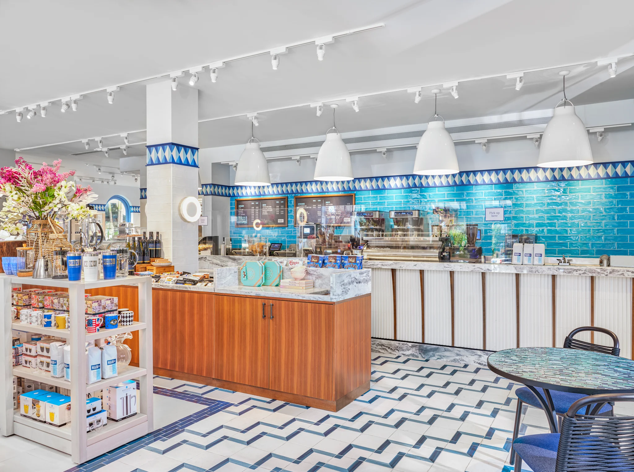 Modern cafe interior with bright blue subway tile walls, white pendant lights, and chevron floor.