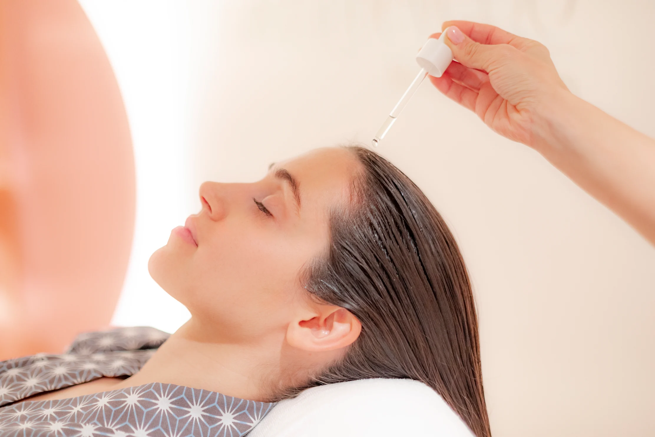 Woman receiving facial serum treatment with dropper applicator during spa session