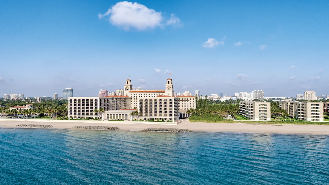 Beachfront view of The Breakers Palm Beach hotel with twin towers and terracotta roof viewed from turquoise ocean waters.