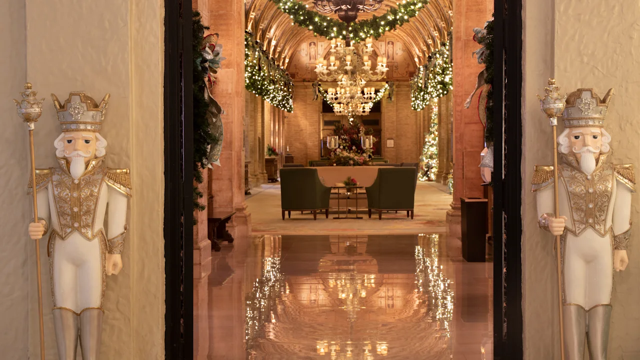 Elegant hotel lobby with gold and white nutcracker statues, chandeliers, and holiday garland decor.