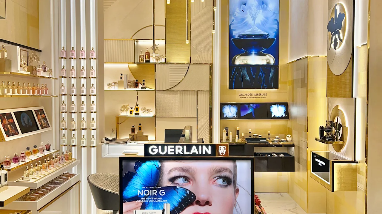Luxury Guerlain cosmetics store interior with gold accents, pendant lights, and makeup display.