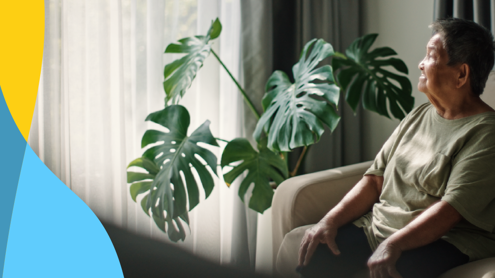 Person on the couch sitting while practicing deep breathing techniques with a monstera plant in the background.