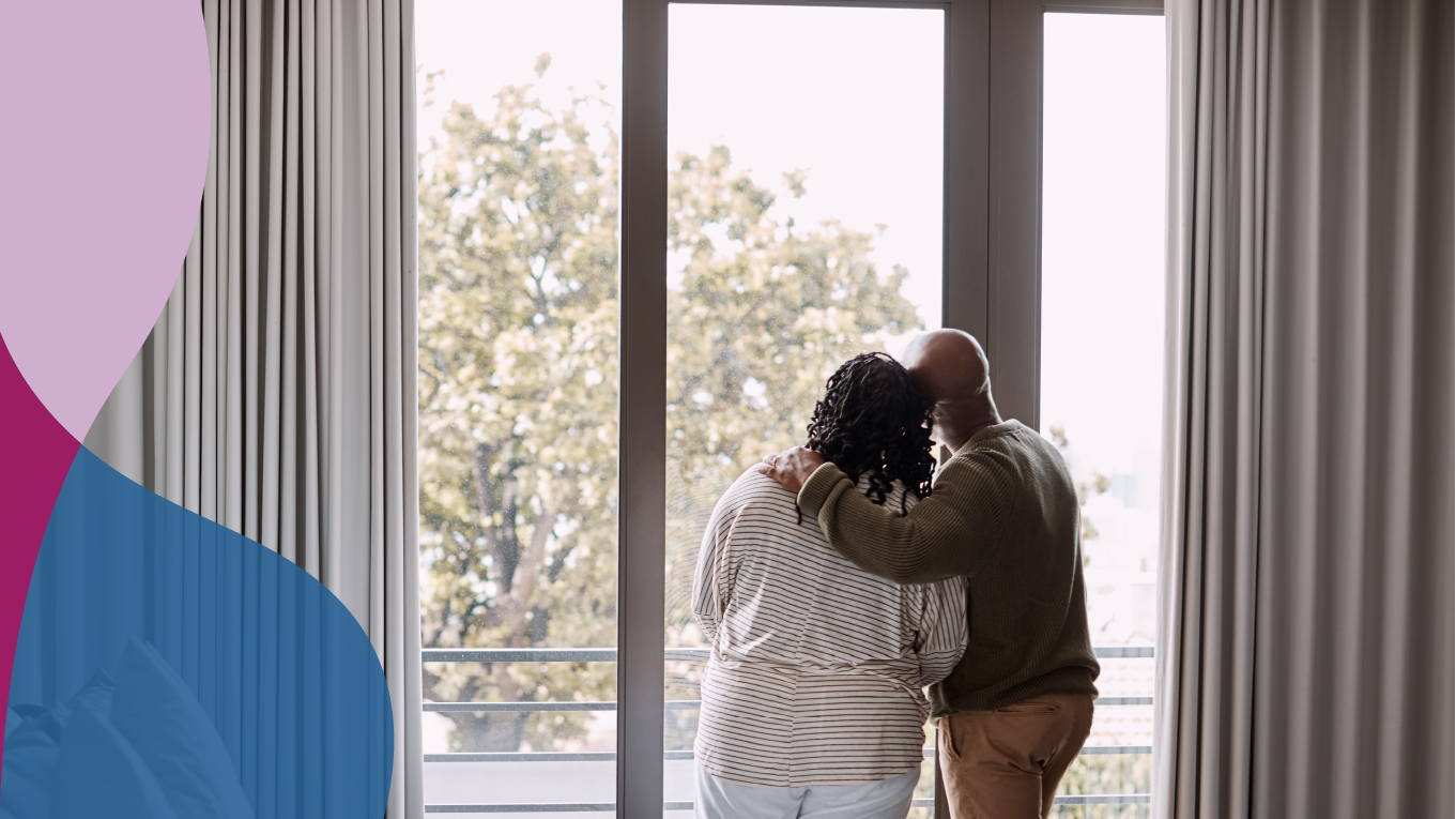 Woman and man standing in front of a glass door, looking outside.