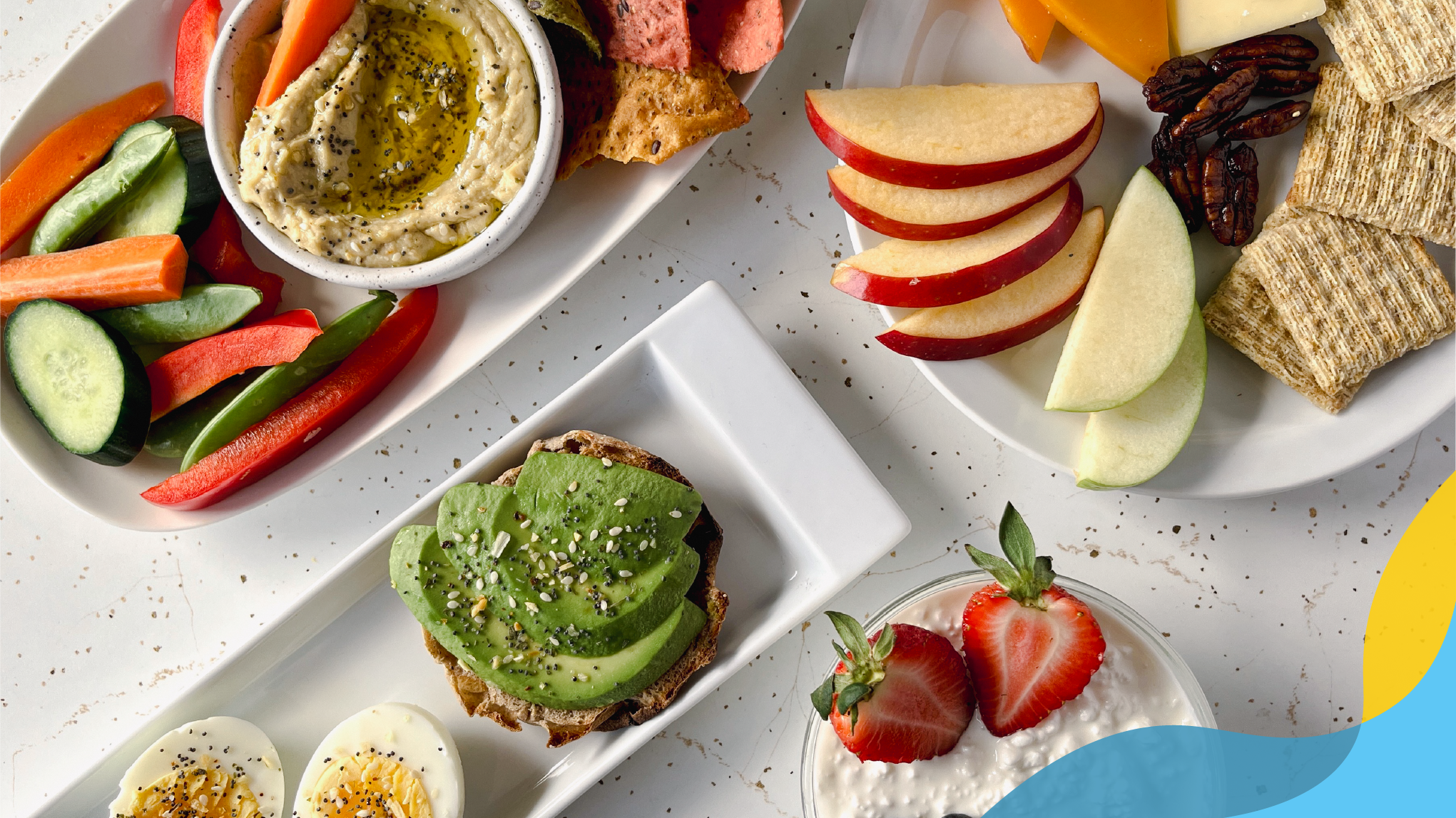 Colorful snacks: hummus with cucumbers, carrots, peppers; apples with cheese, crackers, nuts; avocado toast with hardboiled eggs