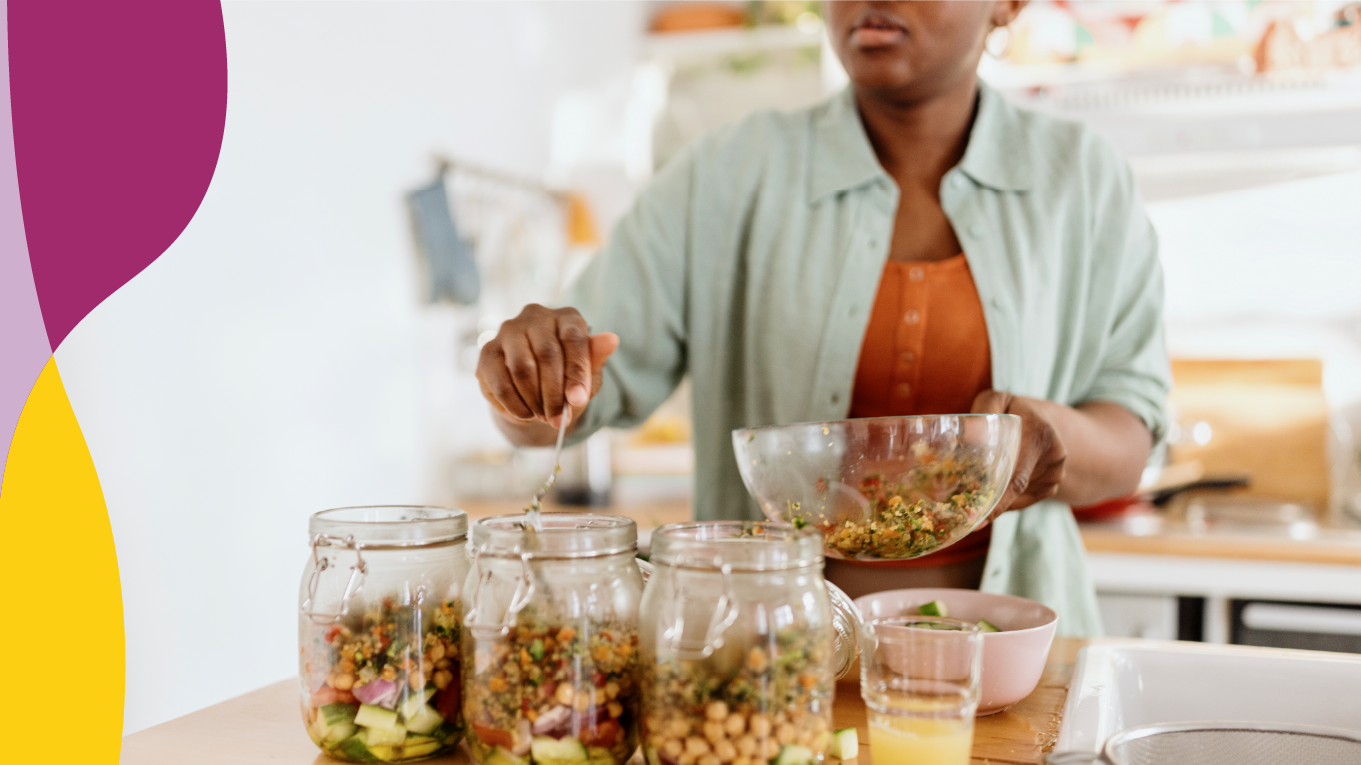 Black woman making mason jar salads for meal prep.