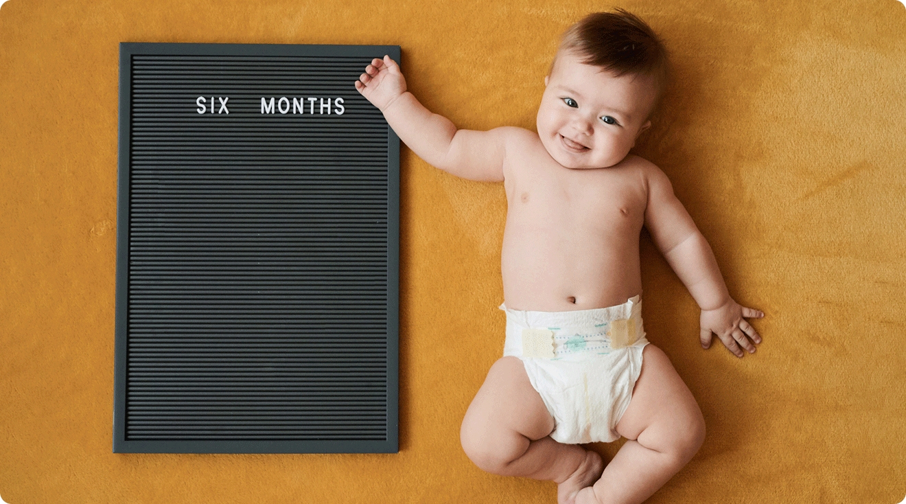 baby with six month old sign showing monthly baby progress photo