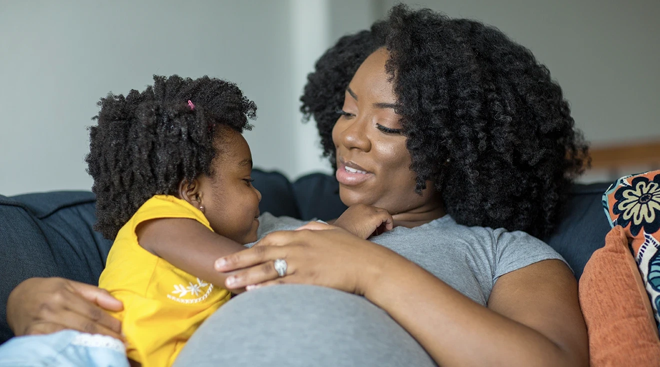 pregnant mom sitting with toddler daughter at home