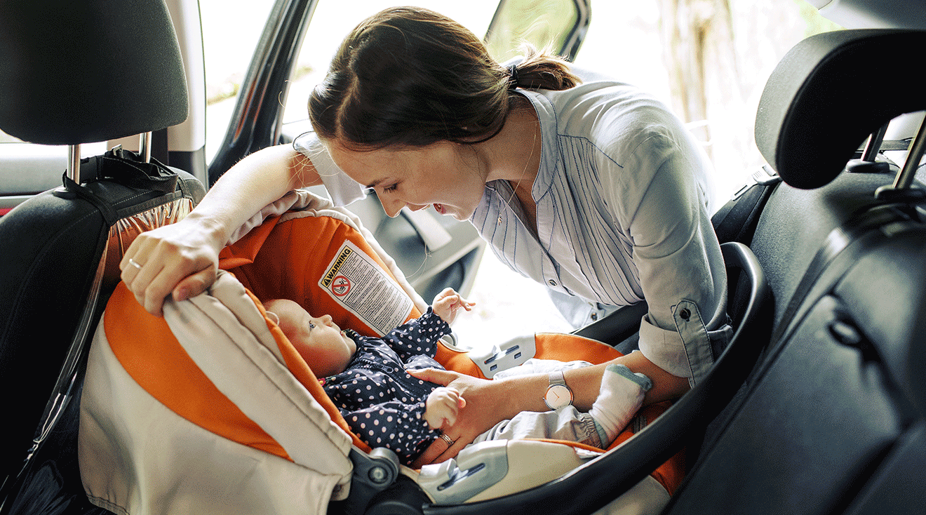 mom putting baby into car seat in car