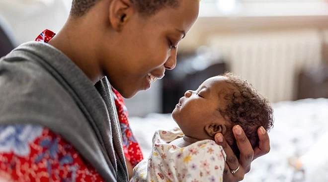 mother holding newborn baby at home and smiling