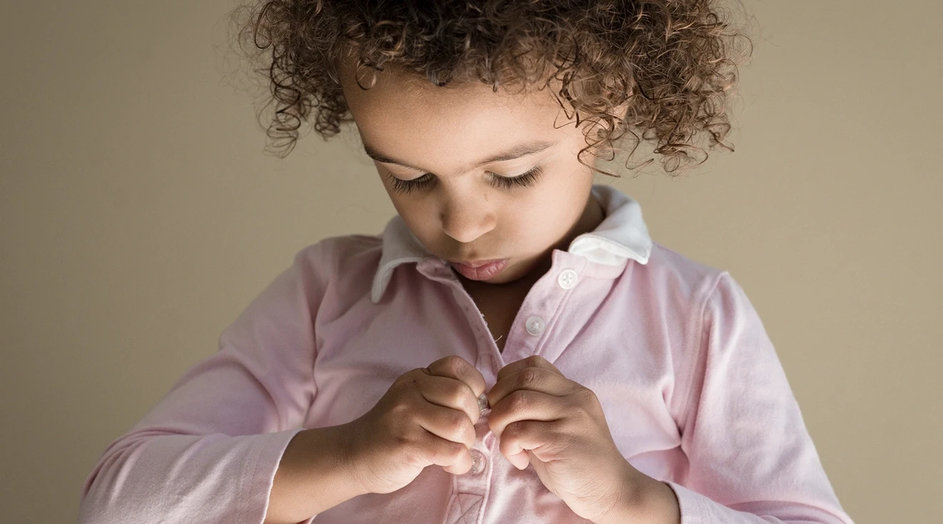toddler fastening buttons on shirt