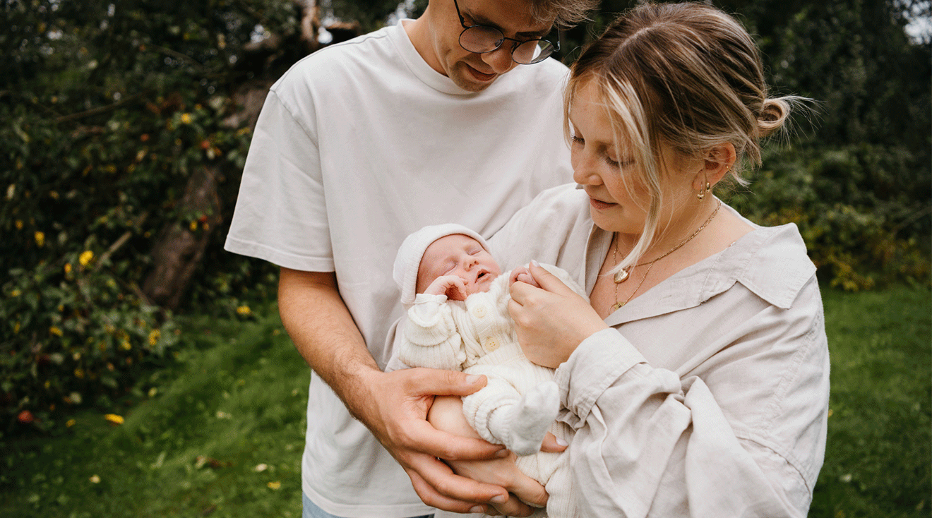 mom and dad holding newborn baby outside