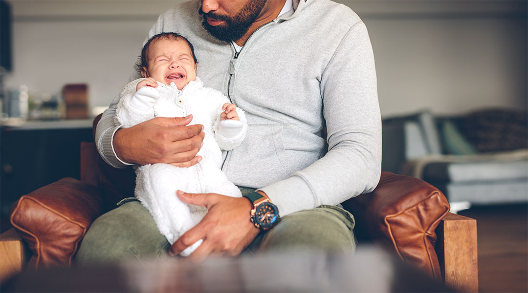 dad holding upset, crying baby