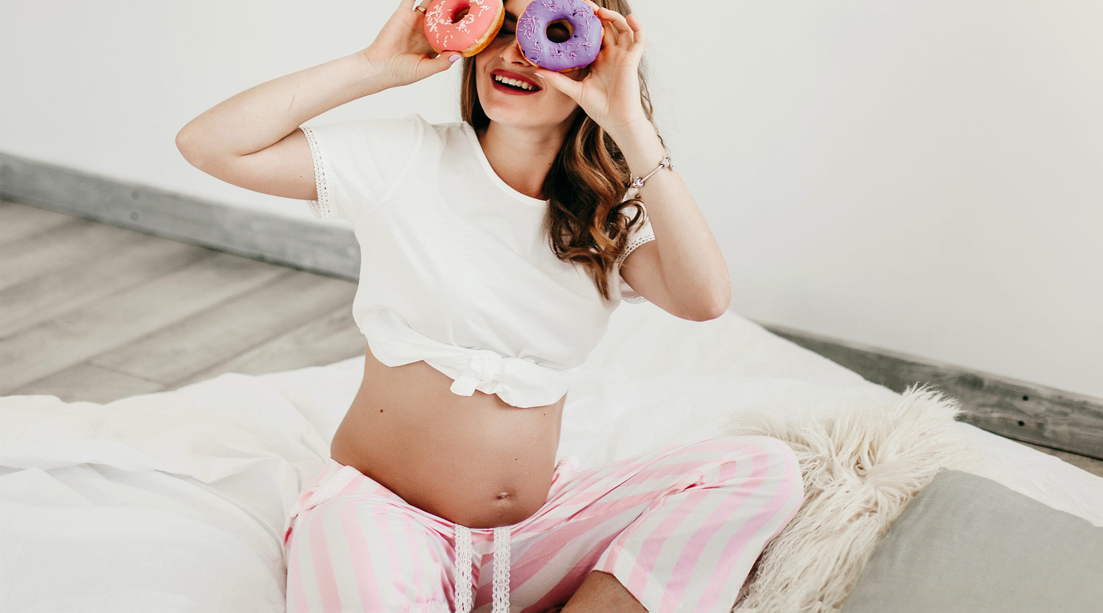 pregnant woman laughing and holding doughnuts up to her eyes