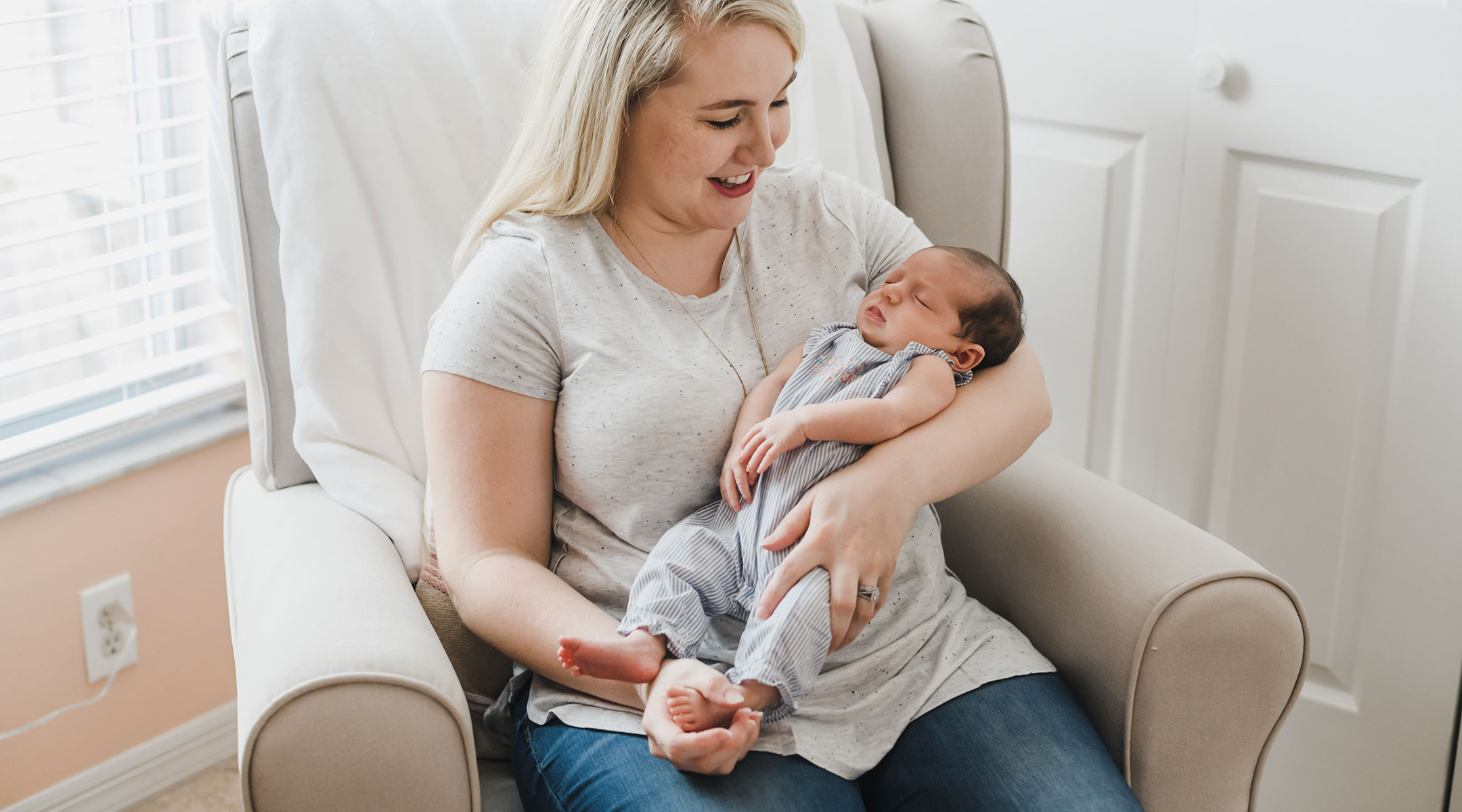 mom holding her newborn baby in the glider and soothing to sleep