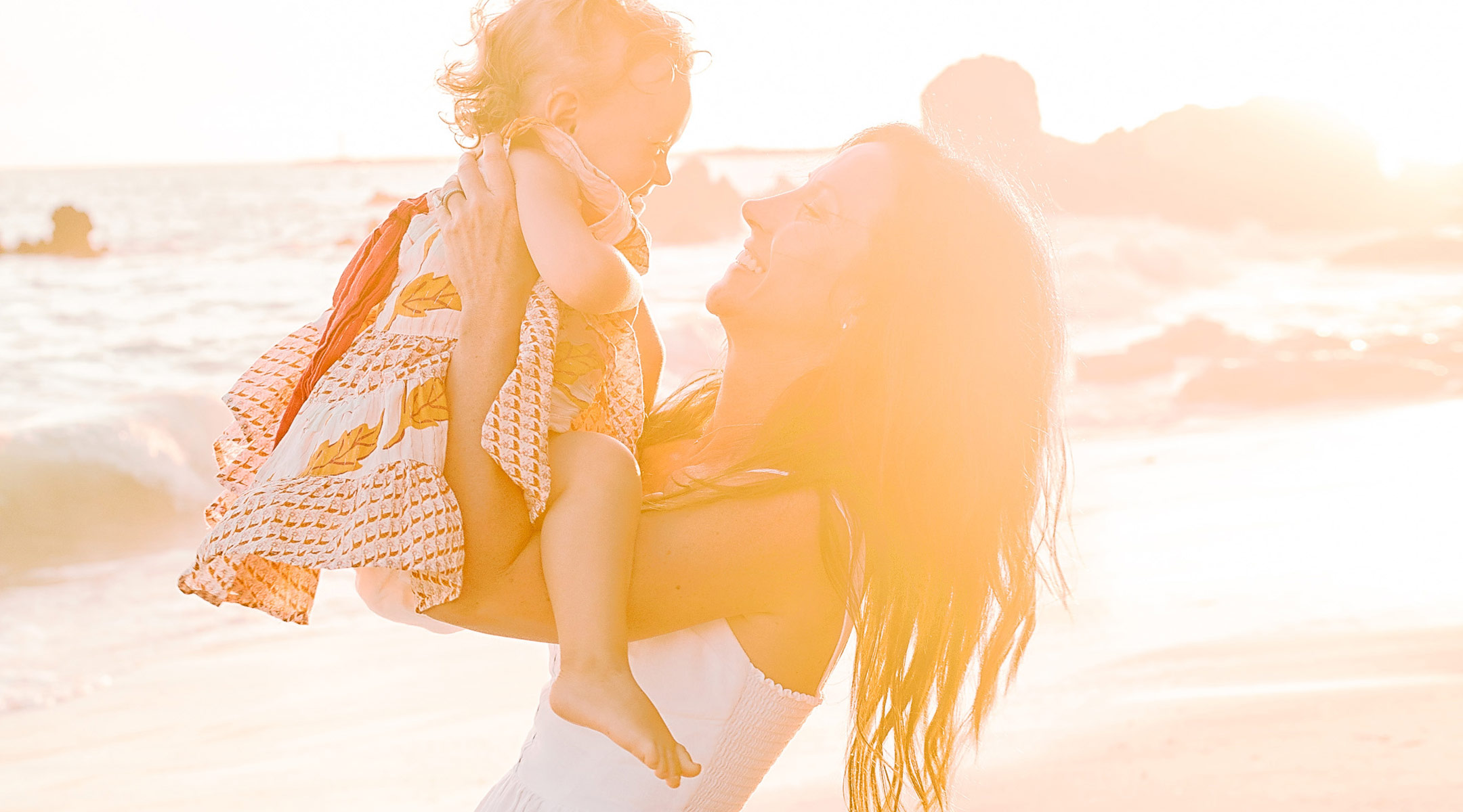 happy mom holding her daughter at the beach