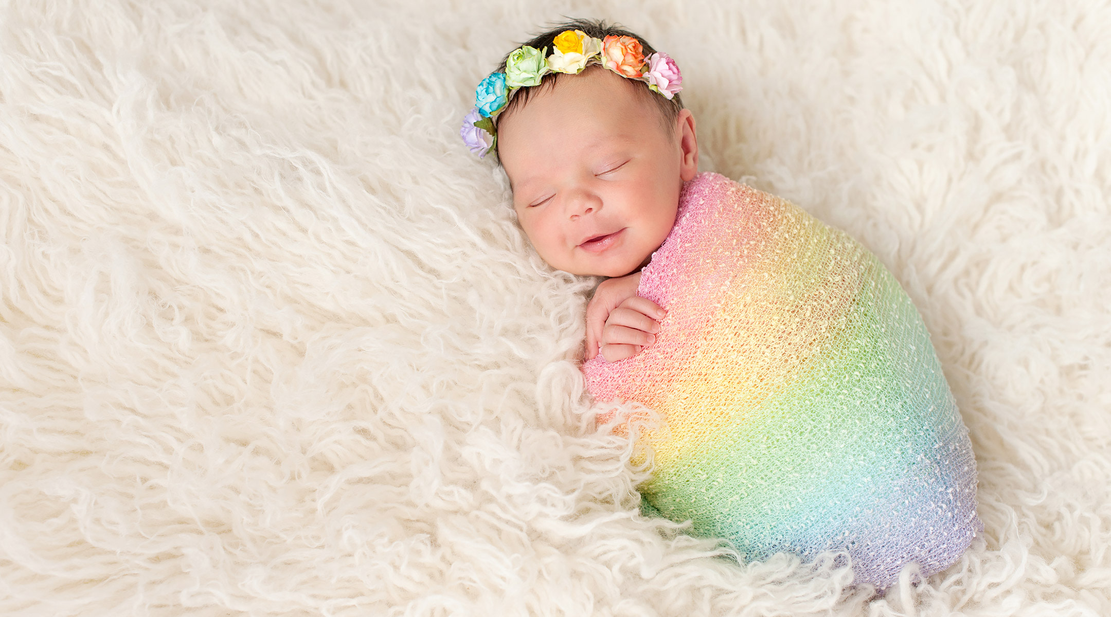 Rainbow baby wearing rainbow blanket