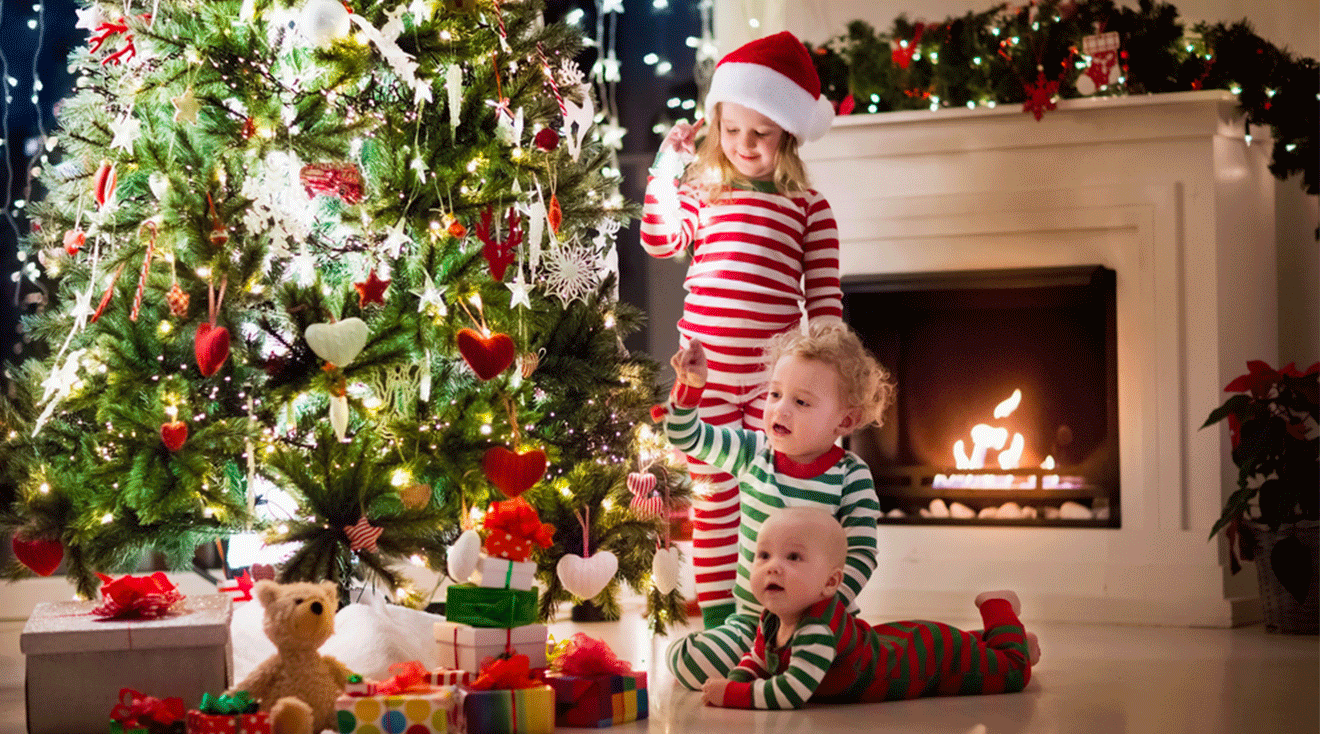 three small children playing near the christmas tree at home