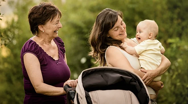 grandmother smiling at daughter and grandchild outside during a walk