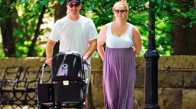 amy schumer walking her baby in a stroller through the park