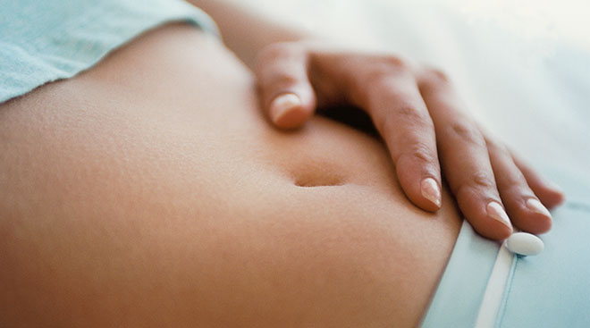 close up of woman's hand on her stomach while lying down