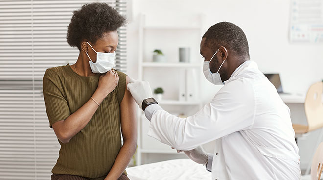 doctor vaccinating black pregnant woman