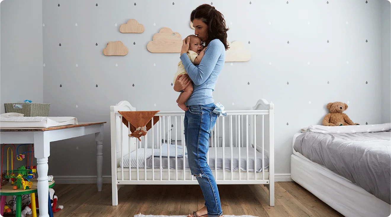 mom holding baby in nursery bedroom at home