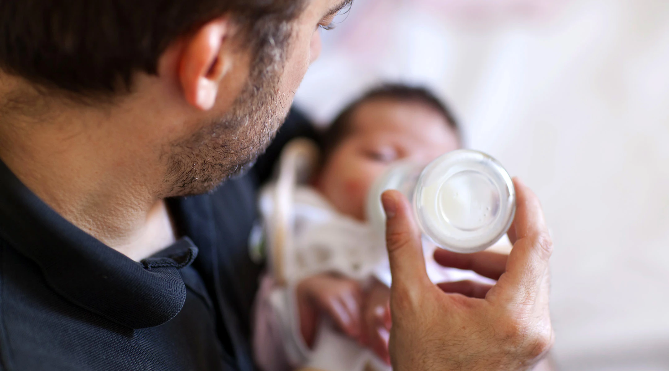 dad feeding newborn baby formula bottle