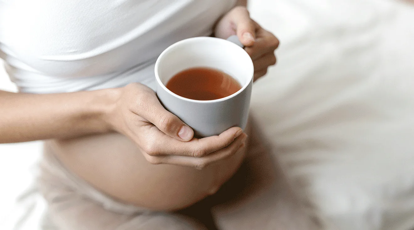 pregnant woman holding a hot mug of tea