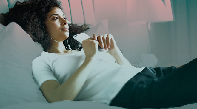 woman listening to her headphones in bed