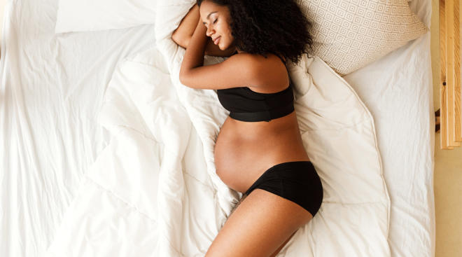 pregnant woman in bed sleeping on her side
