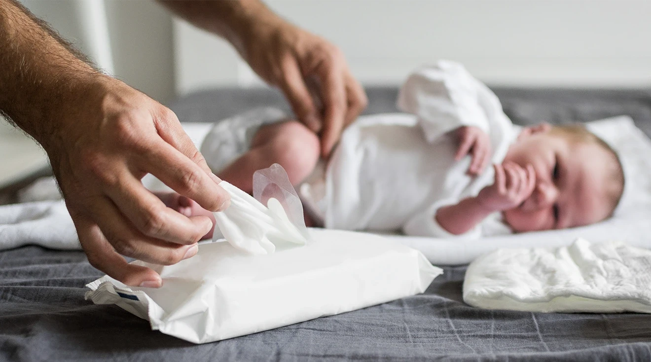 father using baby wipes to change baby's diaper