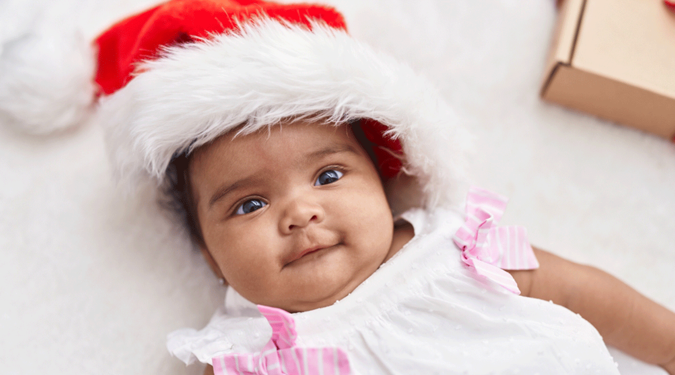 baby lying on floor wearing christmas hat at home