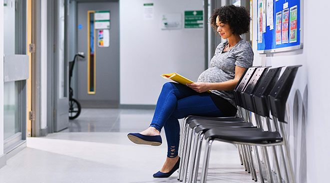 Pregnant woman alone in doctor's office waiting room. 