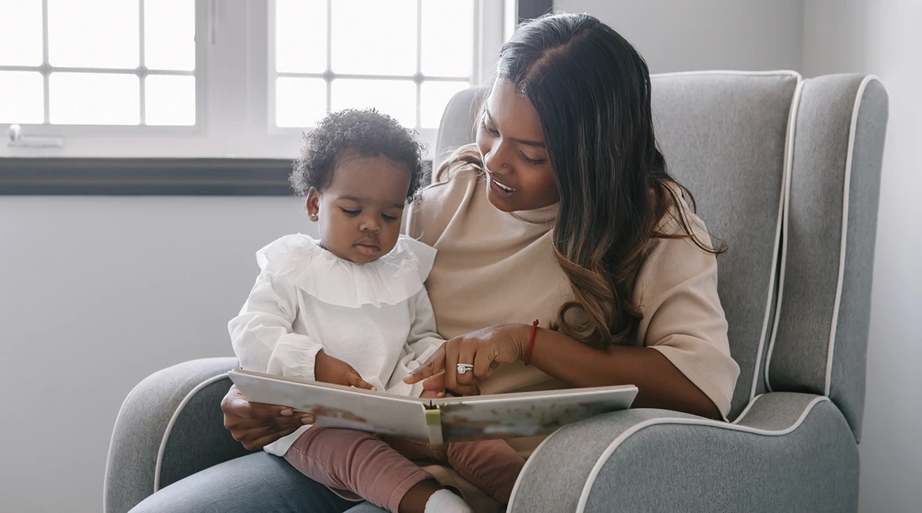 mother reading with baby on rocking chair in nursery room