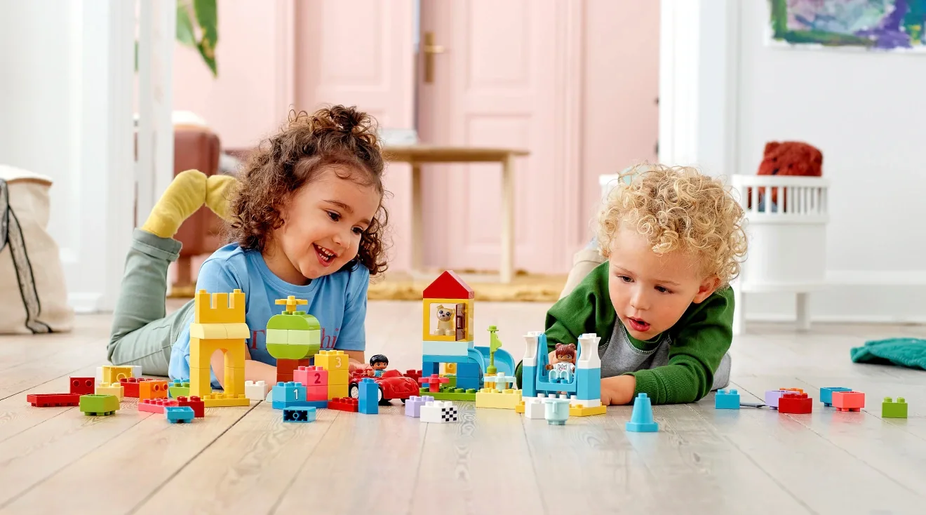 toddlers playing with legos on the floor at home