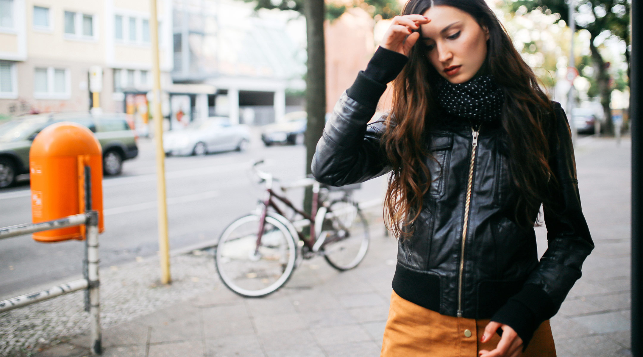 woman walking in urban environment and touching her forehead