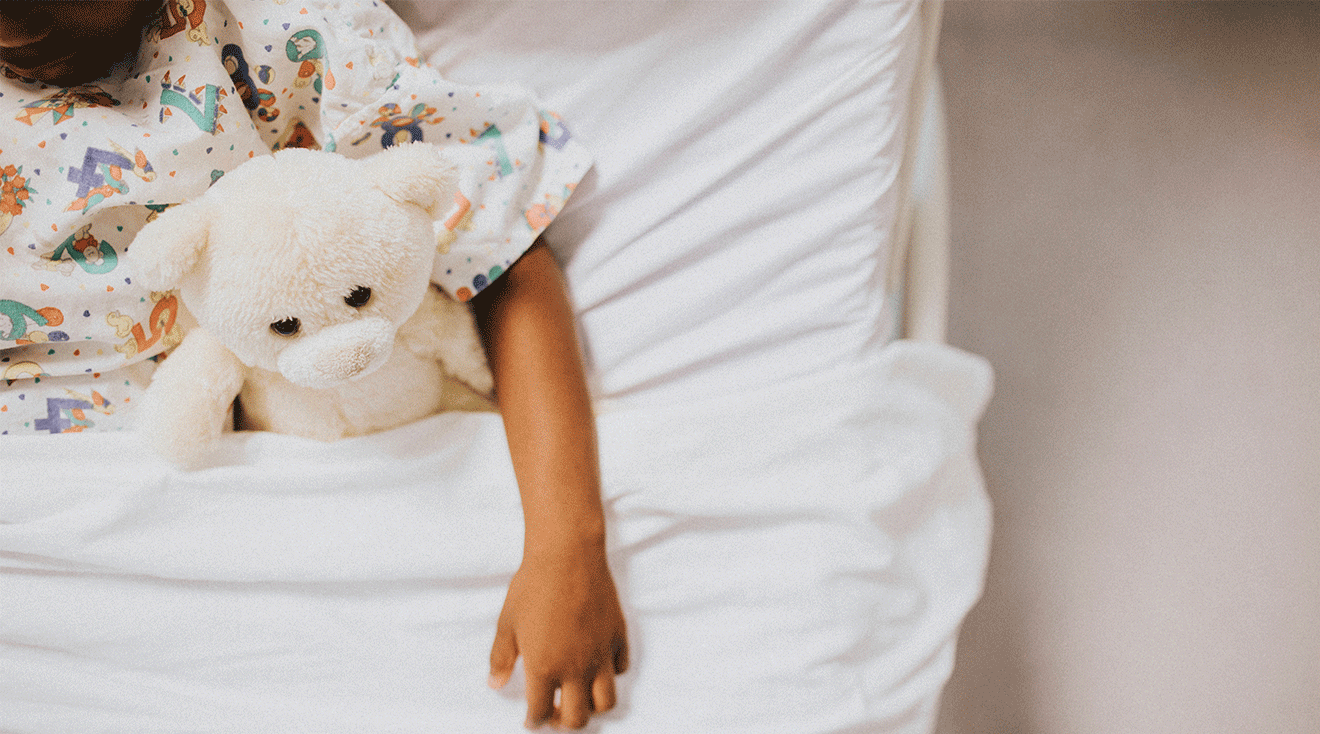 little girl sleeping in hospital bed with teddy bear