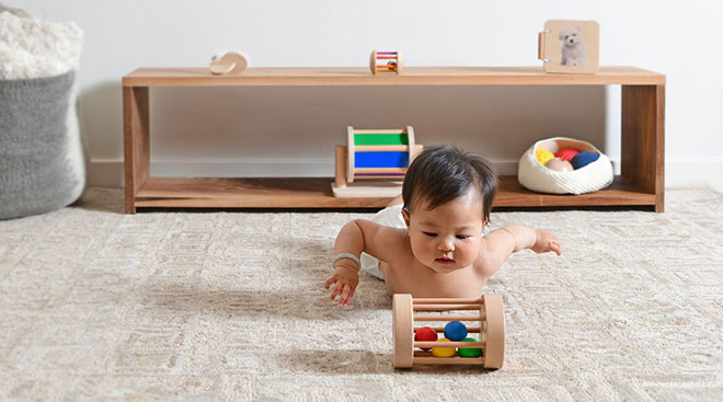 baby plays with wooden toy from his montessori style shelf