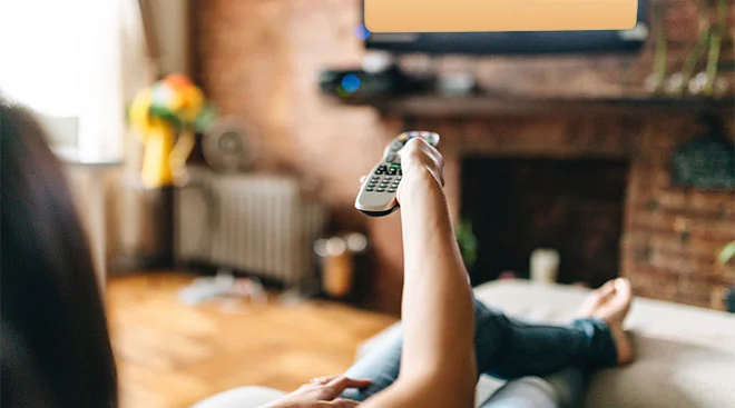 woman watching tv with remote in hand
