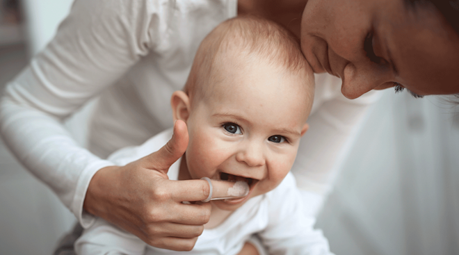 mother brushing baby's teeth