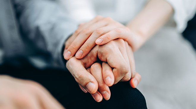 Close-up of couple comforting each other by holding hands. 