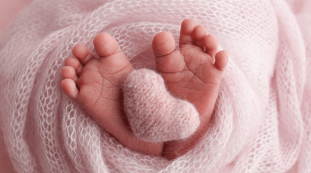 baby feet wrapped in pink blanket with heart