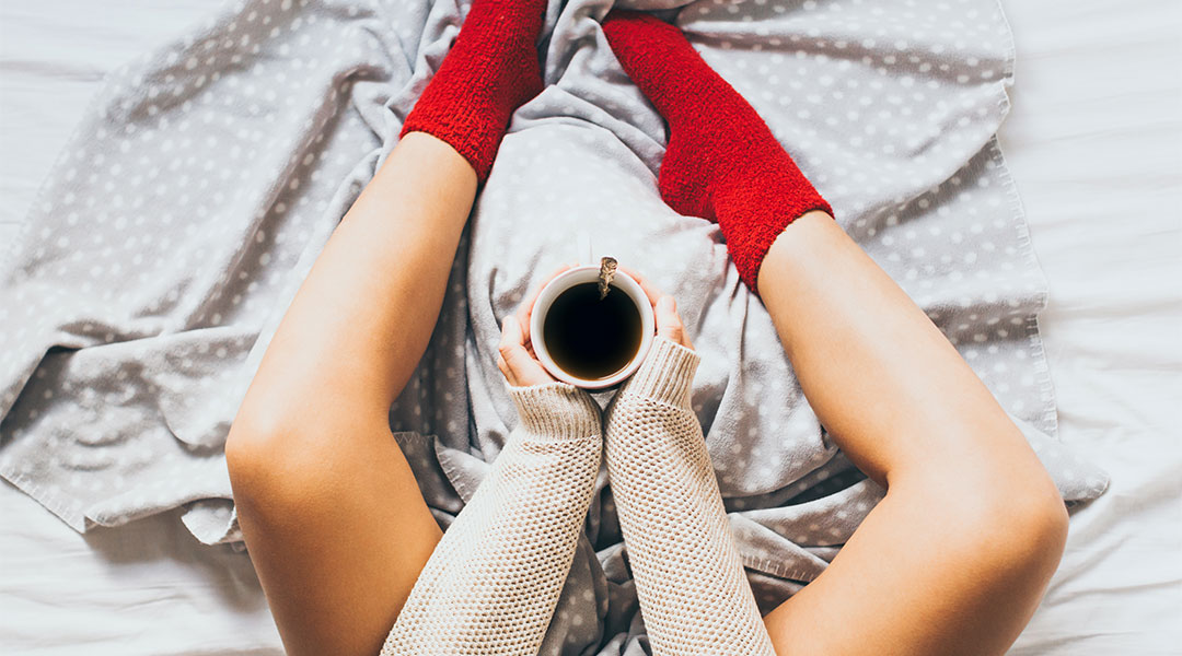 woman wearing red socks and resting her legs in bed