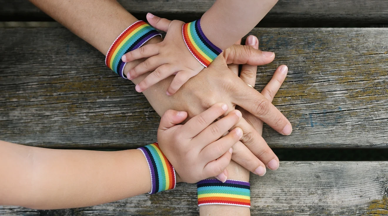 family's hands with rainbow pride bracelets