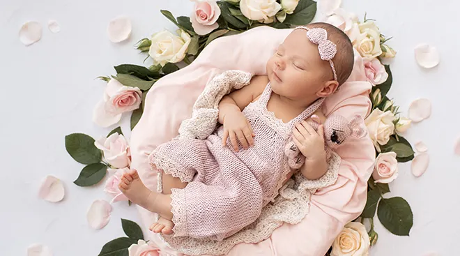 newborn baby sleeping on a pile of flowers