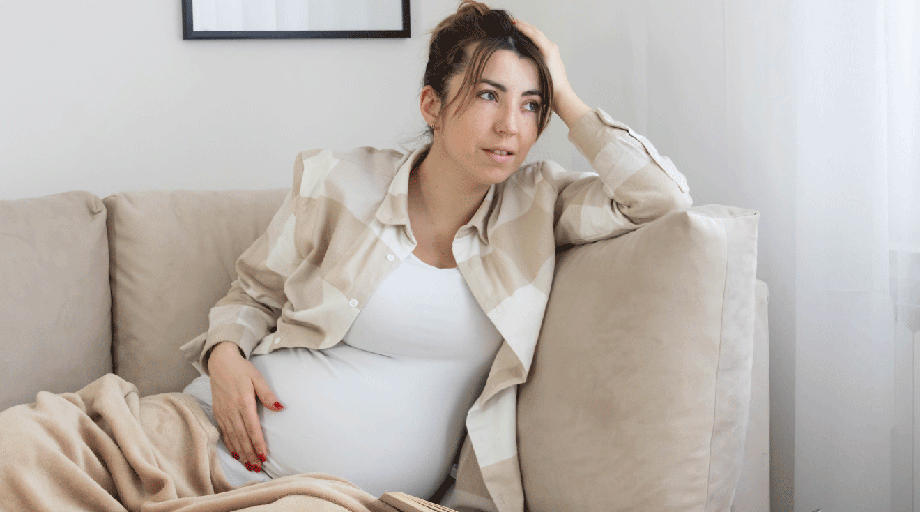 pregnant woman sitting on couch with blanket